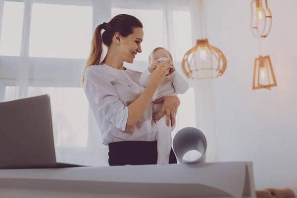 Радостная мать смеется, когда ее маленькая девочка пьет молоко
