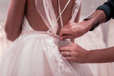 Close up of a wedding dress being fastened clipart