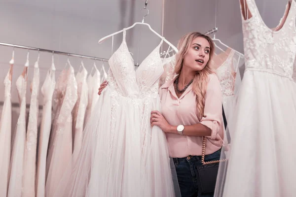 Pleasant young woman looking at the wedding dresses — Stock Photo, Image