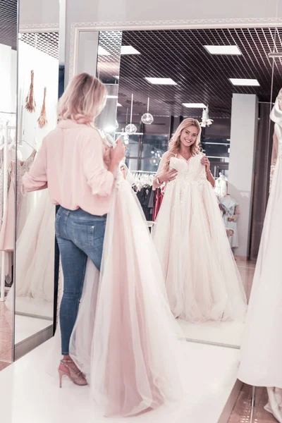 Joyful delighted woman looking at the wedding dress