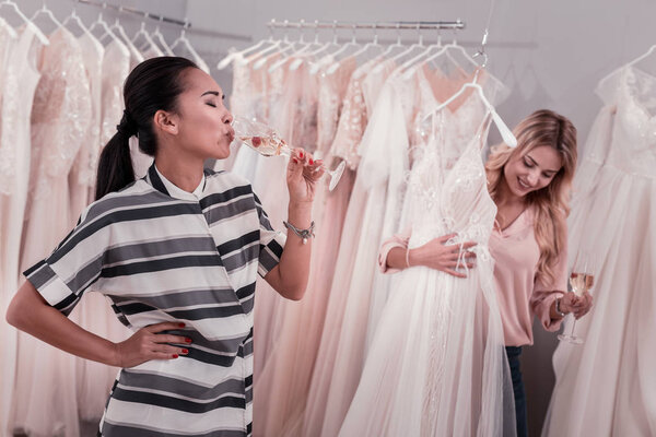 Приятная молодая азиатка пьет игристое вино.
