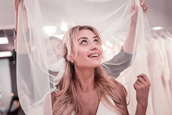 Delighted blonde woman looking at her veil