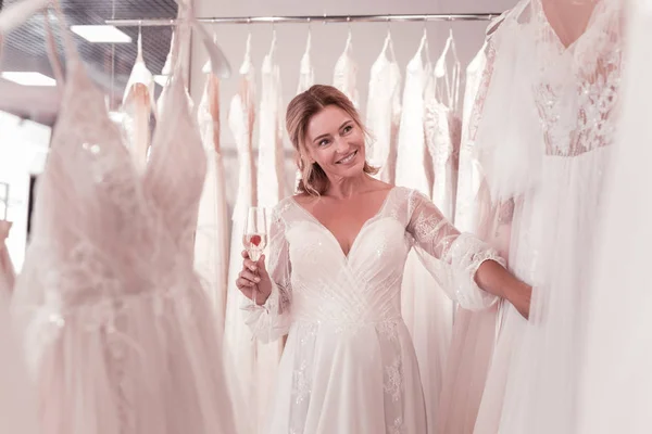 Счастливая позитивная женщина смотрит на свадебные платья — стоковое фото