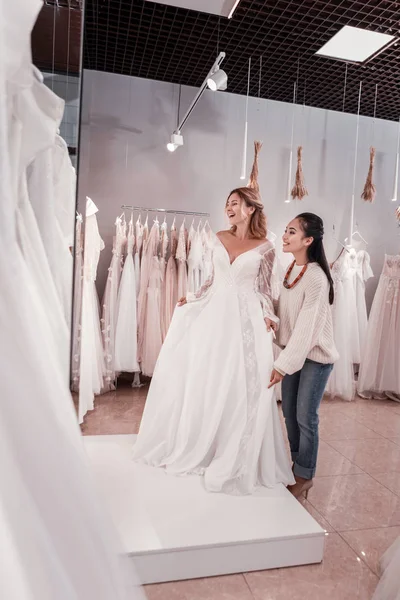 Mulher feliz agradável tentando em um vestido de noiva — Fotografia de Stock