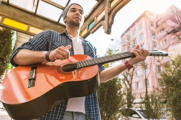 Doordachte mannelijke gitarist opleiding spelen op straat — Stockfoto