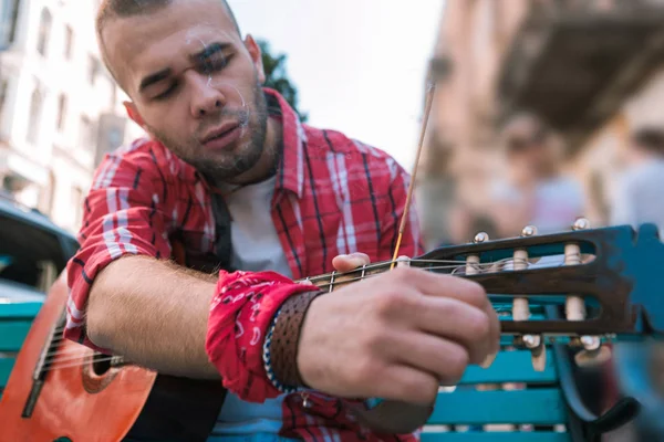 Fokuserade gatumusikant förbereder gitarr före föreställningen — Stockfoto