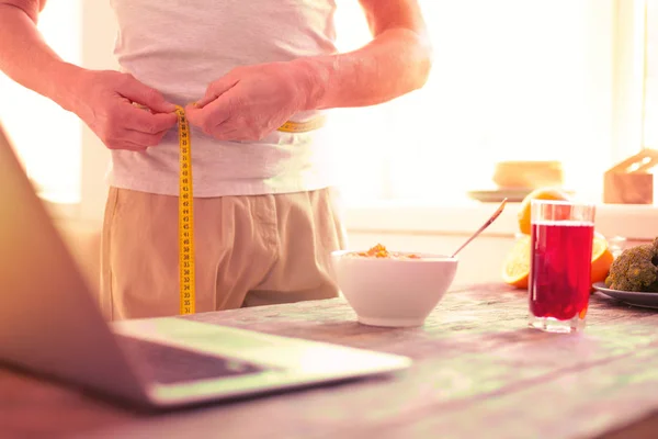 Agréable homme mesurant sa taille dans la cuisine — Photo