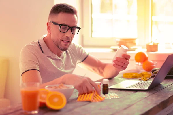 Ретельно концентрований приємний чоловік вибирає різні вітаміни — стокове фото