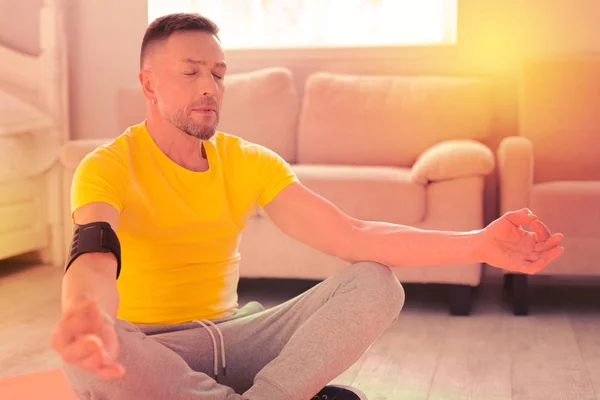 Homem bonito pacífica fazendo ioga no chão em casa — Fotografia de Stock