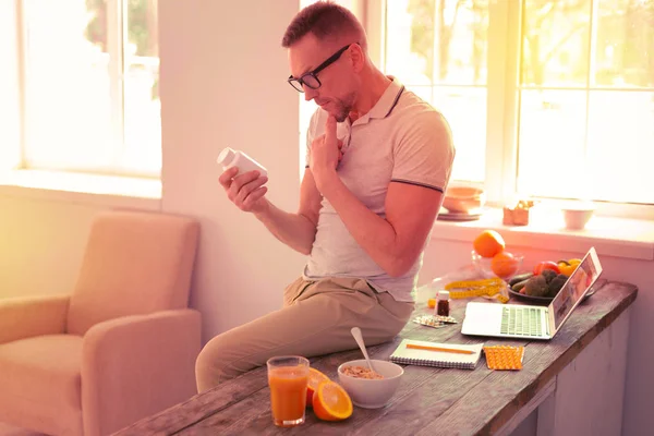 Concentrated nice man holding different medicine in the hand — Stock Photo, Image