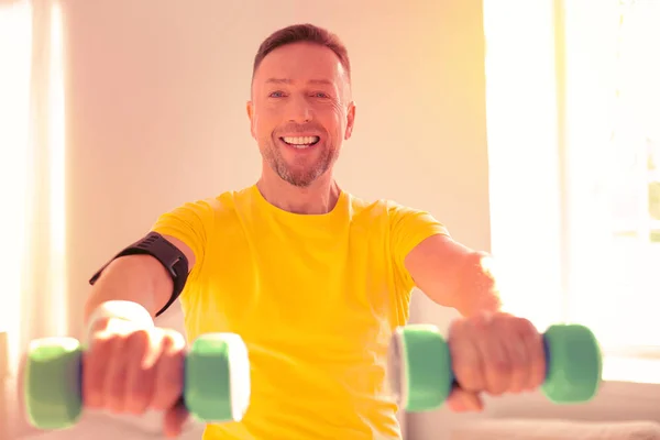 Sonriente guapo hombre entrenando duro en casa — Foto de Stock