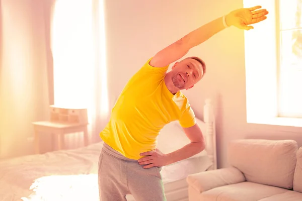 Целеустремленный хороший человек делает упражнения в светлой комнате — стоковое фото