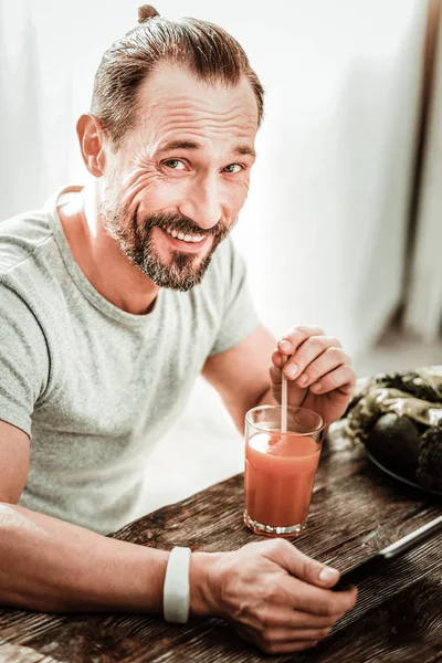 Encantado hombre positivo disfrutando de su jugo de naranja — Foto de Stock