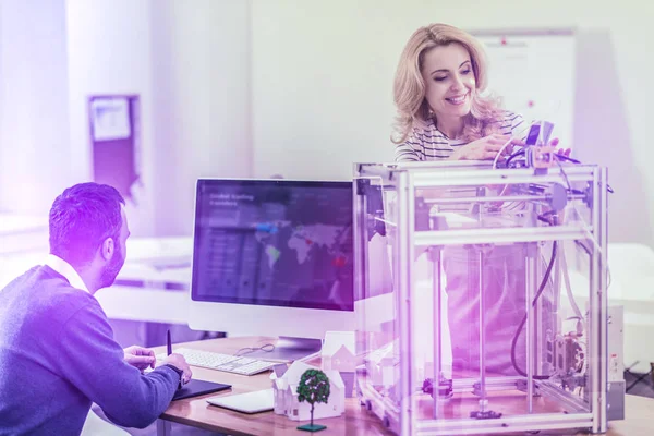 Светловолосая бизнесвумен, стоящая рядом со своим коллегой возле 3D-принтера — стоковое фото