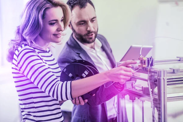 Dunkeläugiger bärtiger Mann hilft seiner Frau bei der Arbeit im Büro mit modernem Drucker — Stockfoto