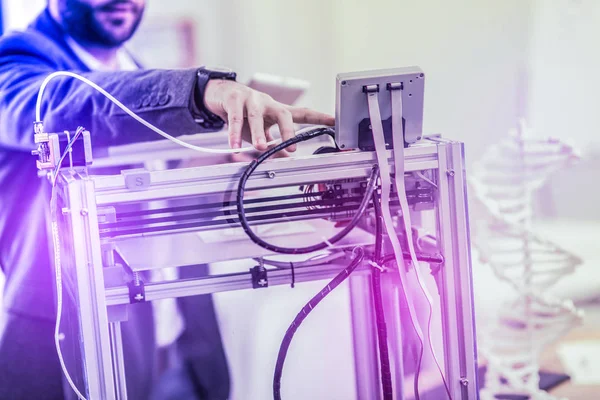 Bearded businessman wearing dark jacket standing near big laser printer in the office — Stock Photo, Image