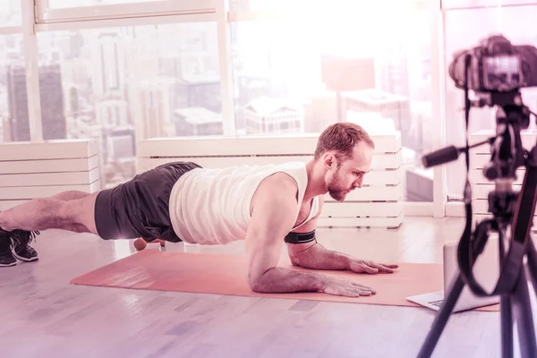 Entrenador concentrado haciendo tutoriales de flexiones en casa —  Fotos de Stock