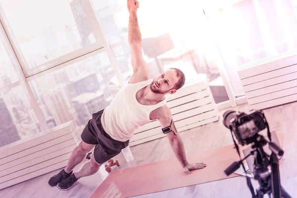 Skilled handsome athlete stretching his hands in front of window — Stock Photo, Image