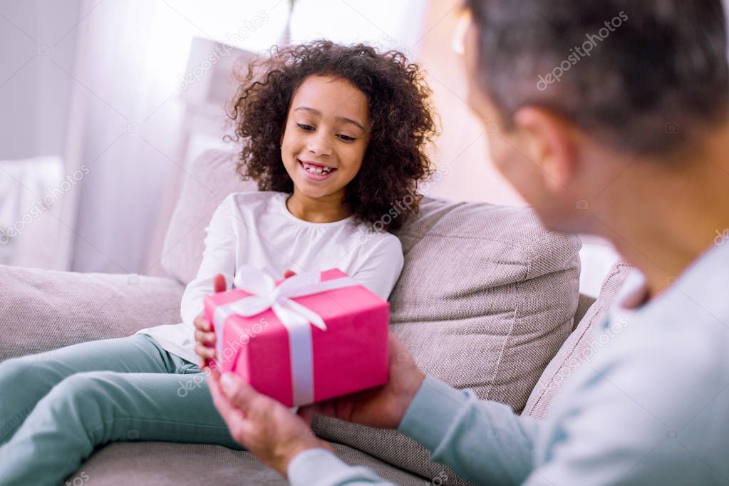 Cheerful girl taking present from her father