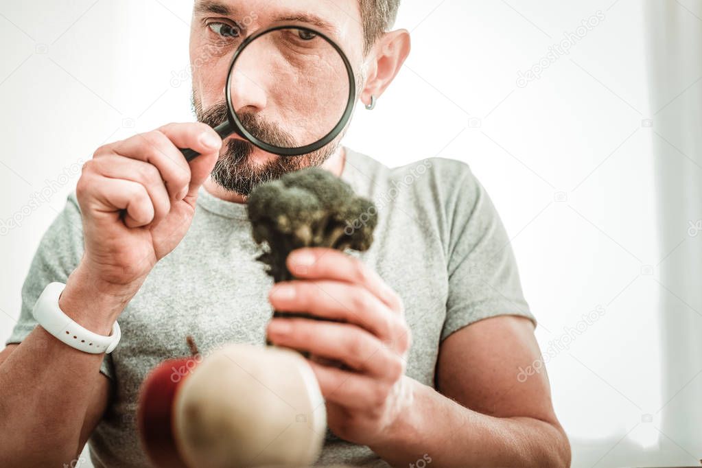 Serious smart man looking into the magnifying glass