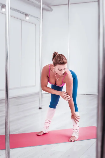 Dunkelhaarige Pole-Tänzerin trägt pinkfarbenes Sport-Top, das ihren Körper streckt — Stockfoto