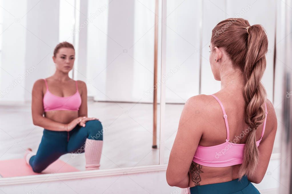 Slim and fit woman with tattoo on her ribs enjoying amazing yoga time