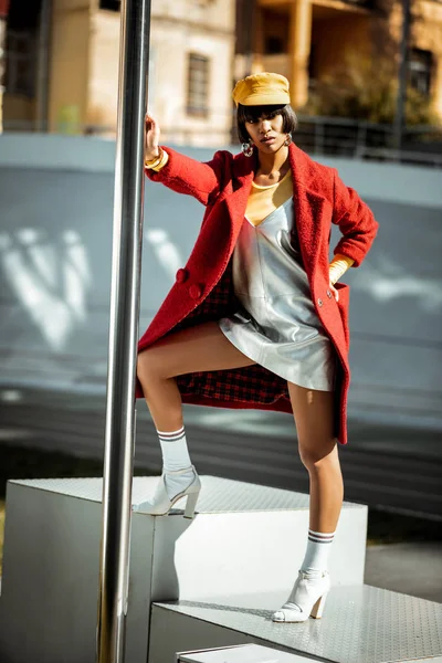 Dissatisfied fashionable woman leaning on wide metal pole — Stock Photo, Image