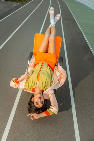 Atypische dunkelhaarige Frau, die ihre Beine über dem Stuhl kreuzt — Stockfoto