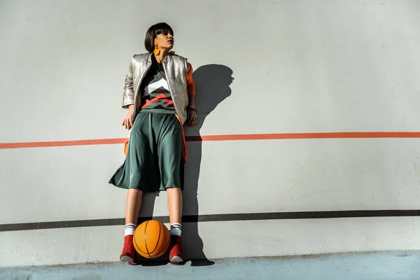 Чарівна худа дівчина залишається на стіні з м'ячем між ногами — стокове фото