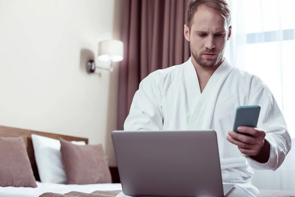 Bărbat cu barbă așezat pe pat dublu după ce s-a trezit în camera de hotel — Fotografie, imagine de stoc