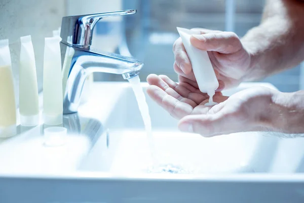 Älterer Mann schnurrt etwas Seife auf seine Hände, während er sich das Gesicht wäscht — Stockfoto