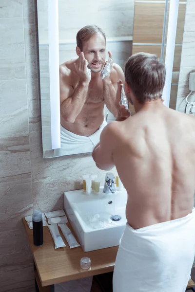 Красивый мужчина с красивым мускулистым телом бреет лицо после душа — стоковое фото