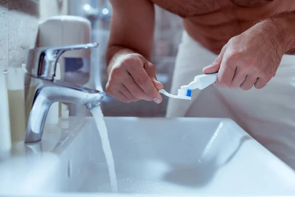 Kypsä mies laittaa hammastahnaa hänen hammasharja aamulla — kuvapankkivalokuva