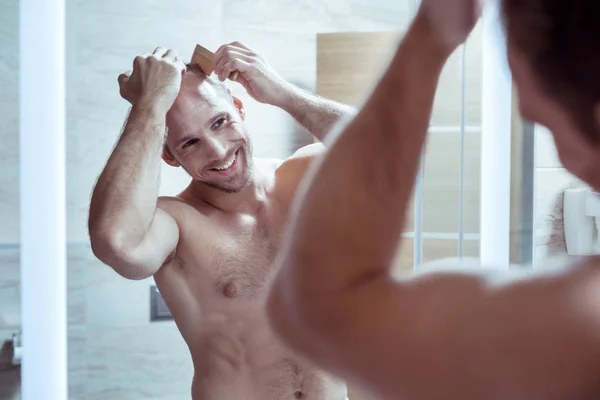 Przystojny Brodaty mężczyzna czuje się wesoły podczas czesania włosów rano — Zdjęcie stockowe