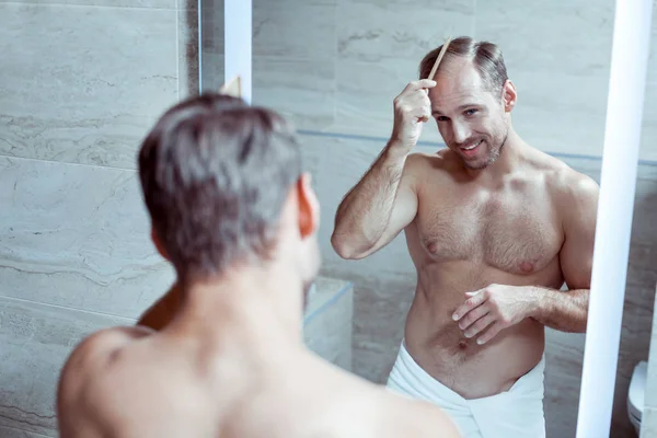 Bello uomo dai capelli biondi pettinarsi i capelli preparandosi per il lavoro — Foto Stock
