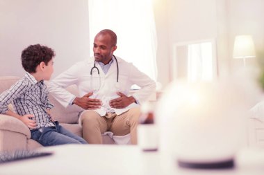 Güzel neşeli erkek doktor midesi holding