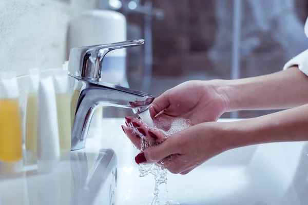 Nainen, jolla on punainen kynsitaide pesee kätensä kylpyhuoneessa — kuvapankkivalokuva