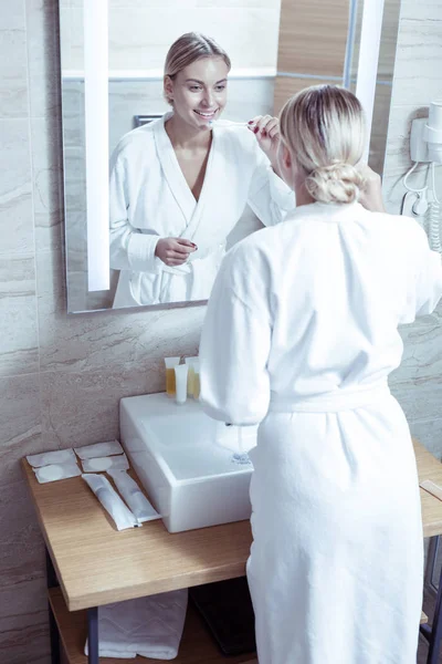 Vonzó, csinos nő visel fehér fürdőköpeny, fogmosás — Stock Fotó