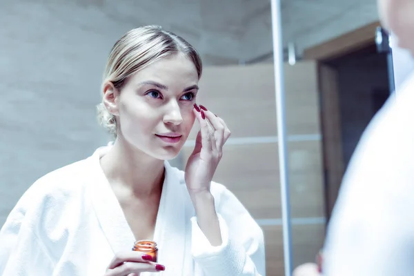 Vacker ung kvinna med röda naglar tar hand om hennes hud på ansikte — Stockfoto