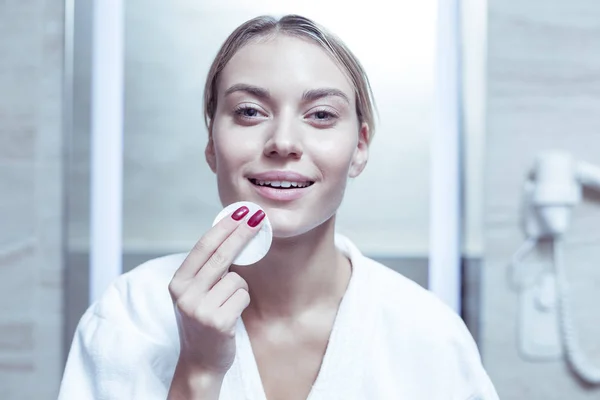 Mujer alegre de pelo rubio sintiéndose feliz quitando el maquillaje — Foto de Stock