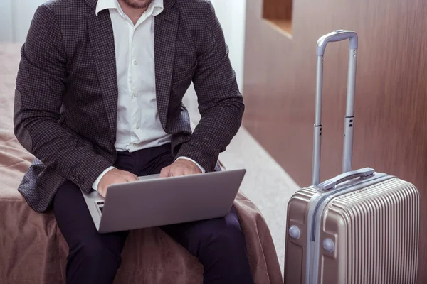 Top view of businessman on business trip near his luggage with laptop