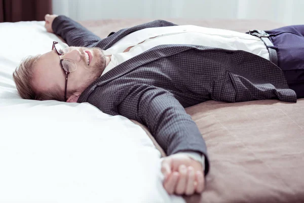 Elegante hombre de negocios barbudo tumbado en la cama de hotel agradable pantano después de un largo día —  Fotos de Stock