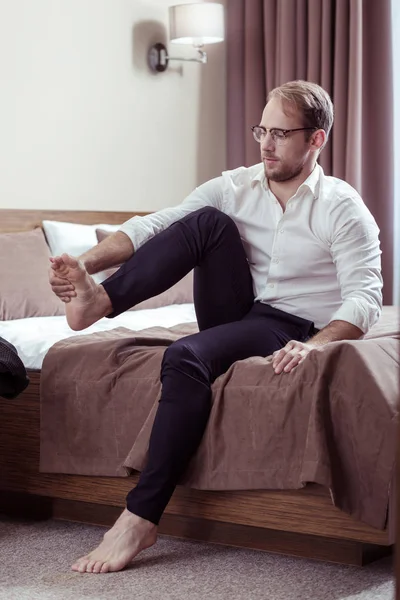 Uomo d'affari che indossa gli occhiali togliersi le scarpe dopo una giornata difficile — Foto Stock