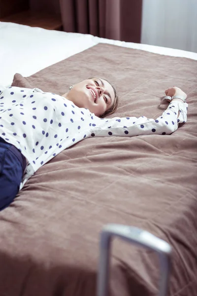 Stylish elegant woman wearing white spotted blouse lying on hotel bed — Stock Photo, Image