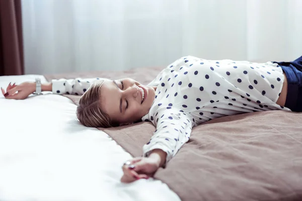 Hermosa mujer rubia tumbada en la cama en el hotel sintiéndose cansada —  Fotos de Stock