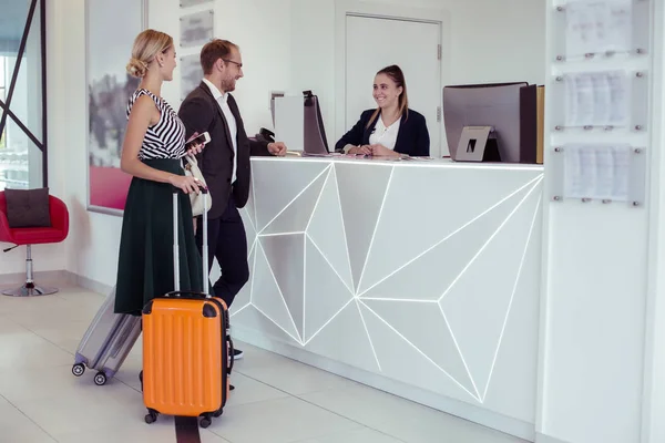 Succesvolle paar van zakenlieden komt naar receptionist in hotel — Stockfoto