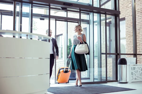 Paar welvarende zakenlieden met bagage invoeren van hotel — Stockfoto