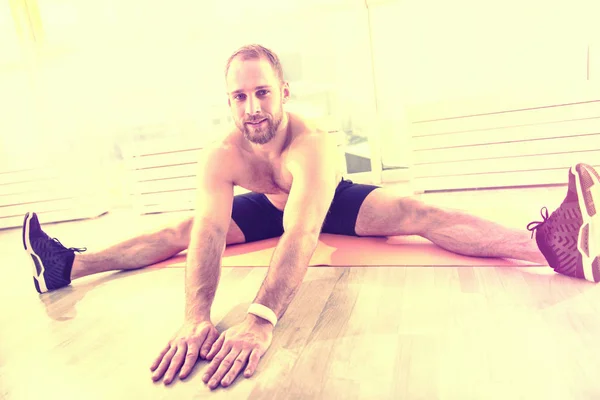 Wysokiej porywający radosny człowiek robi ćwiczenia na podłodze w pokoju światło — Zdjęcie stockowe