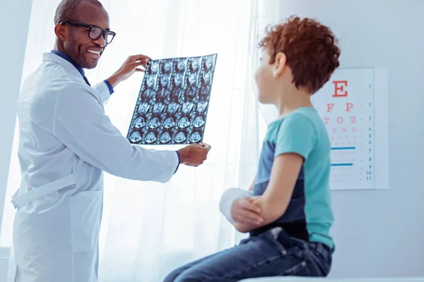 Позитивний дружній лікар, дивлячись на рентгенівське зображення пацієнтів — стокове фото