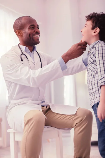 Freudig positiver Arzt, der in den Mund der Jungen schaut — Stockfoto